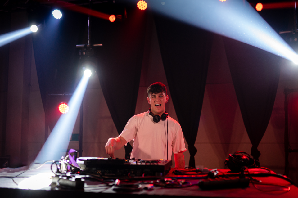 DJ performing with turntables under colorful stage lights