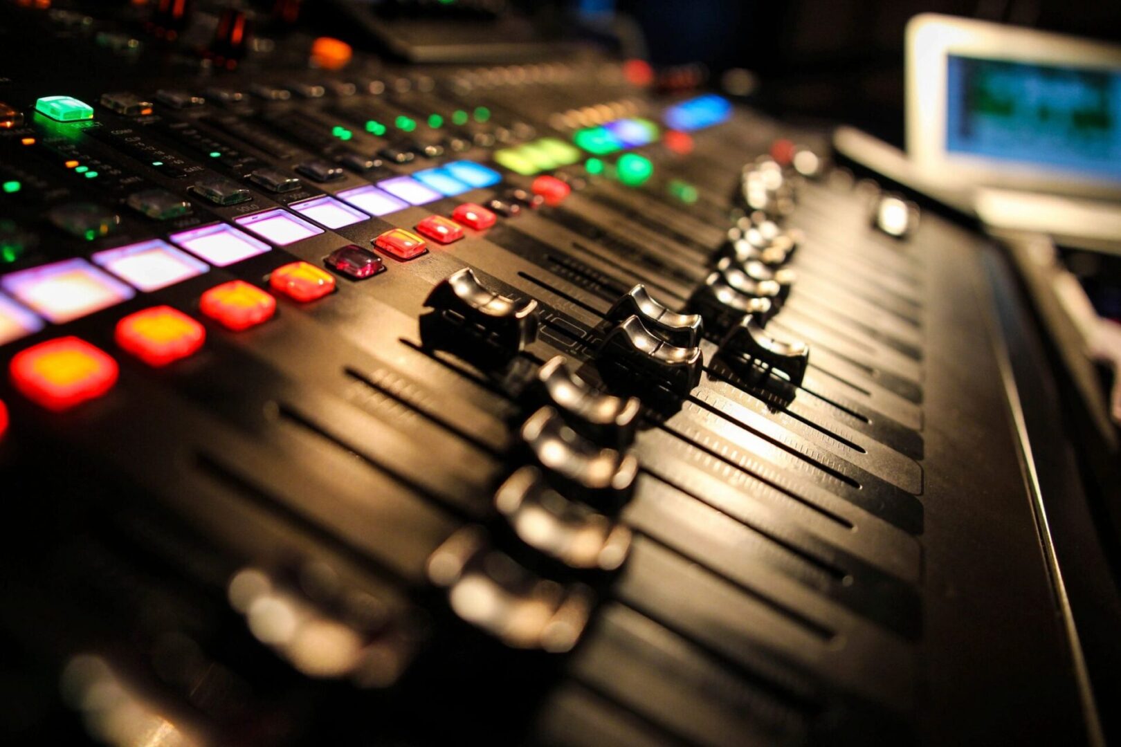 Close-up of audio mixing console faders and lights