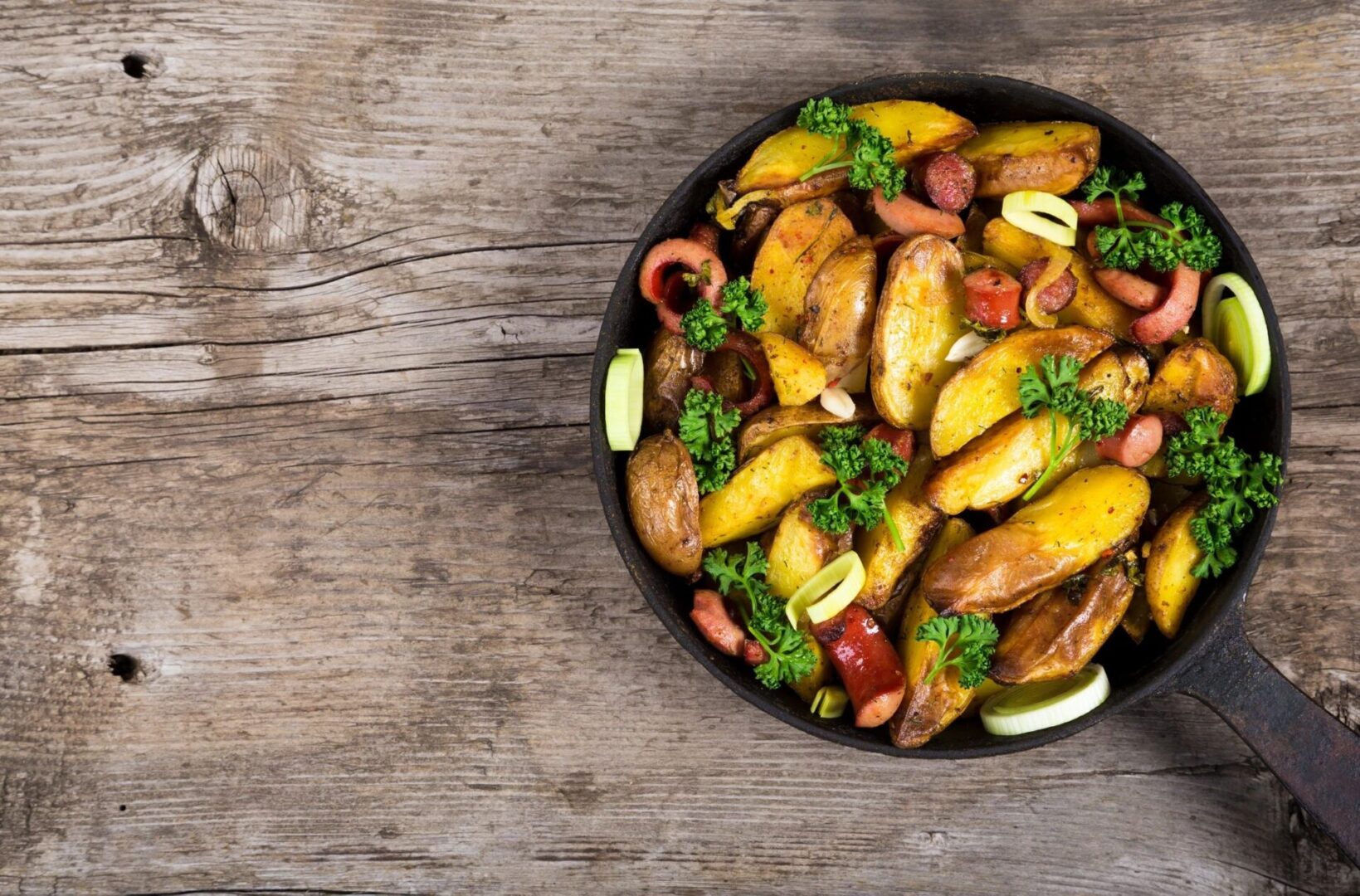Skillet roasted potato wedges with sausages and parsley